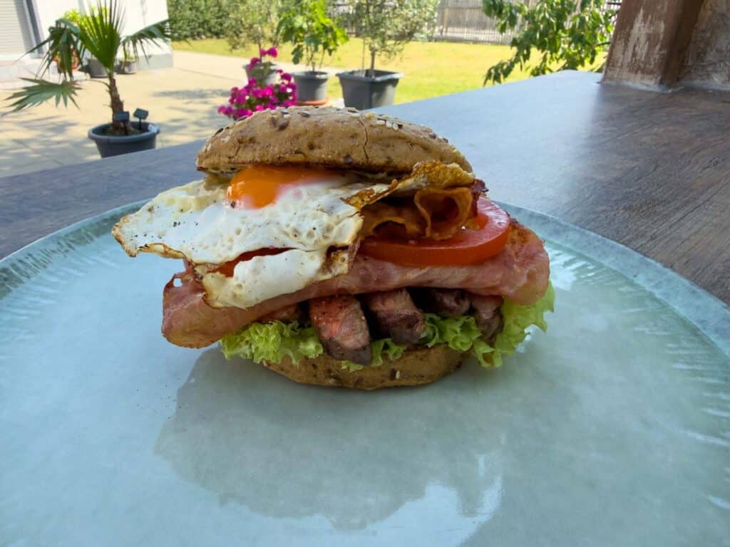 Chivito vom Grill mit Rindfleisch, Speck, Käse und Spiegelei im Brötchen